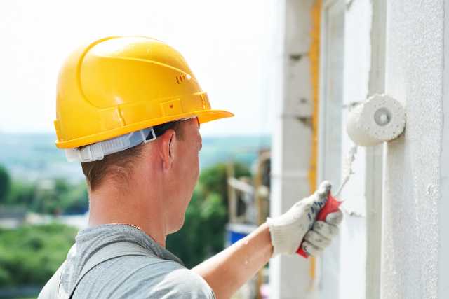 Exterior Commercial Painter with yellow hard hat on and roller