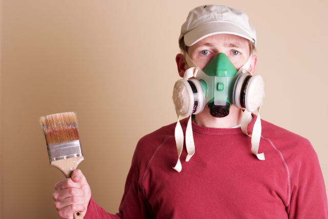 House Painter with a venting mask on and paint brush